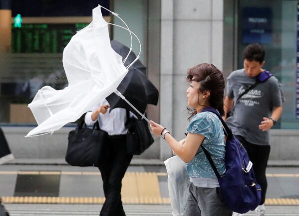 Девушка идет с зонтом во время сильного ветра, вызванного тайфуном Джеби, Токио, Япония