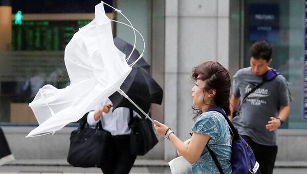 Девушка идет с зонтом во время сильного ветра, вызванного тайфуном Джеби, Токио, Япония