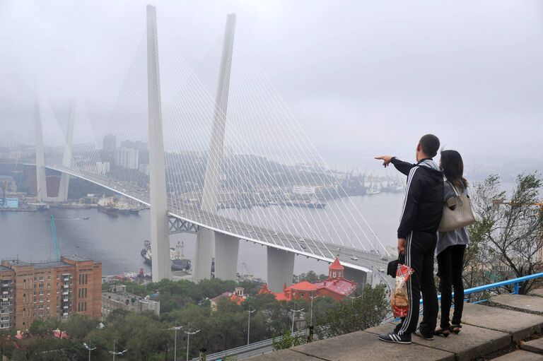 Туристы любуются мостом через бухту Золотой Рог во Владивостоке Туристы любуются мостом через бухту Золотой Рог во Владивостоке