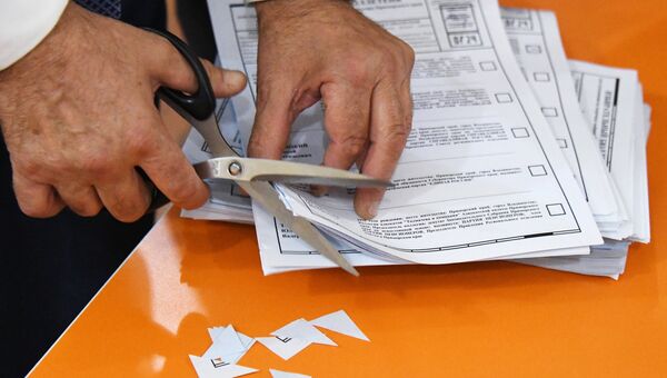 Член избирательной комиссии аннулируют неиспользованные бюллетени во время подсчета голосов на одном из избирательных участков во Владивостоке