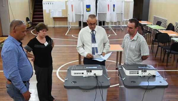 Члены участковой избирательной комиссии вскрывают избирательную урну перед подсчетом голосов в единый день голосования на избирательном участке №817 во Владивостоке. 9 сентября 2018