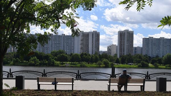 Мужчина сидит на лавочке на набережной Москвы-реки на территории парка 850-летия Москвы в районе Марьино
