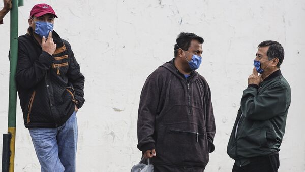 Мужчины, прикрывая лица масками, ждт пока пожарные устранят течь в результате пиратской врезки в газопровод в северной провинции Пуэбла, центральная Мексика. 12 сентября 2018