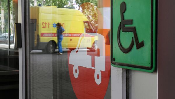 Автомобиль скорой помощи и таблички с символикой на двери здания больницы. Архивное фото