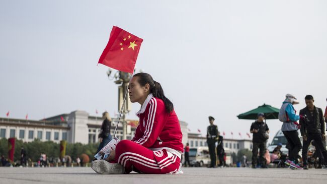 Женщина с флагом Китая на площади в Пекине. Архивное фото