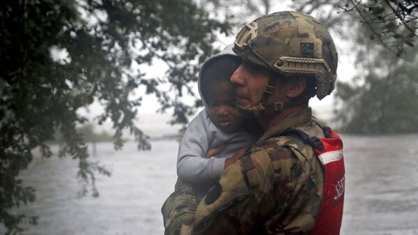 Сотрудник спасательного отряда Национальной гвардии эвакуирует ребенка во время наводнения, вызванного ураганом Флоренс, в Нью-Берне, Северная Каролина. 14 сентября 2018