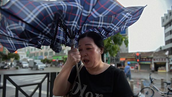 Женщина настигнута порывом сильного ветра, который связан с прибытием тайфуна Мангхута в город Янцзян южнокитайской провинции Гуандун. 16 сентября 2018