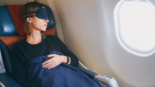 Девушка спит в салоне самолета