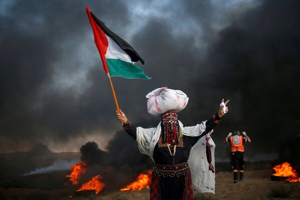 Женщина с флагом Палестины на акции протеста возле границы с Израилем
