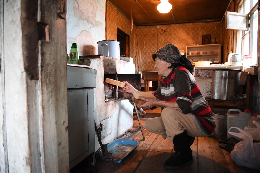 Екатерина Чижова закидывает в печь дрова