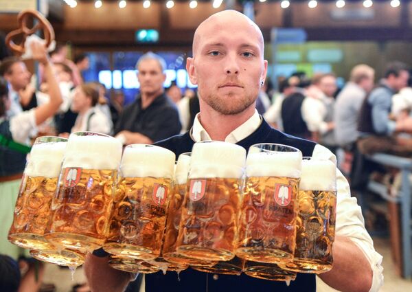 Официант разносит бокалы с пивом на открытии традиционного пивного фестиваля Октоберфест в Мюнхене