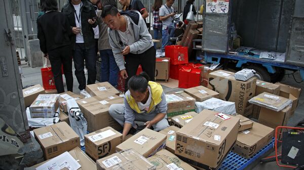Сотрудники службы доставки сортируют посылки возле офисного здания в Пекине 