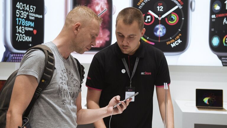 Мужчина рассматривает телефон iPhone XS Max в магазине re:Store торгово-развлекательного центра «Галерея» в Санкт-Петербурге