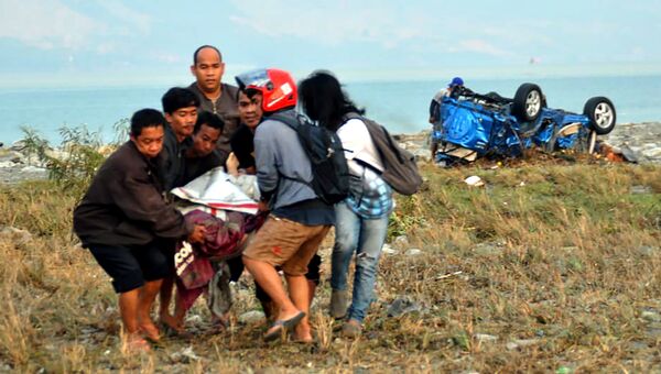 Люди помогают пострадавшему после землетрясения и цунами поразившего город Палу на острове Сулавеси, Индонезия. 29 сентября 2018