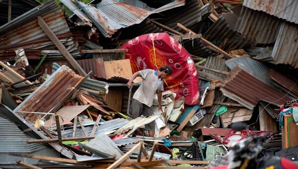 Мужчина ищет свои вещи среди обломков разрушенного дома в городе Палу на острове Сулавеси, где прошло сильное землетрясение и цунами. 29 сентября 2018