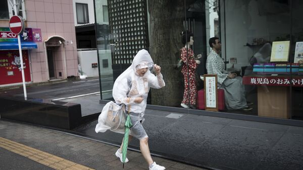 Житель города Кагашима в Японии спасается от погоды испортившейся в связи с приходом тайфуна. Архивное фото