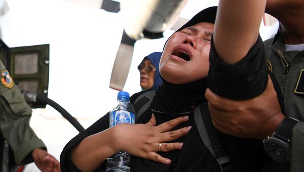 Женщина ожидает эвакуацию после землетрясения и цунами в аэропорту города Палу, остров Сулавеси, Индонезия. 30 сентября 2018