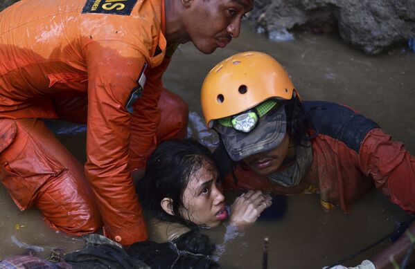 Cпасатели достают девушку из воды после землетрясений и цунами в городе Палу на острове Сулавеси в Индонезии. 30 сентября 2018 года