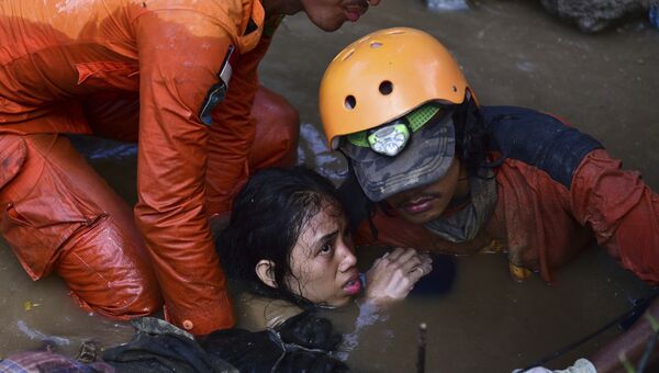 Cпасатели достают девушку из воды после землетрясений и цунами в городе Палу на острове Сулавеси в Индонезии. 30 сентября 2018 года