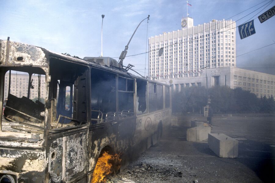 Обгорелый троллейбус у здания Дома Советов Российской Федерации во время интенсивного танкового обстрела