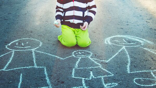 Ребенок рисует на асфальте мелом