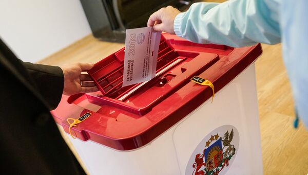 Избиратель опускает бюллетень в урну на избирательном участке во время парламентских выборов в 13-й Сейм Латвии. 6 октября 2018