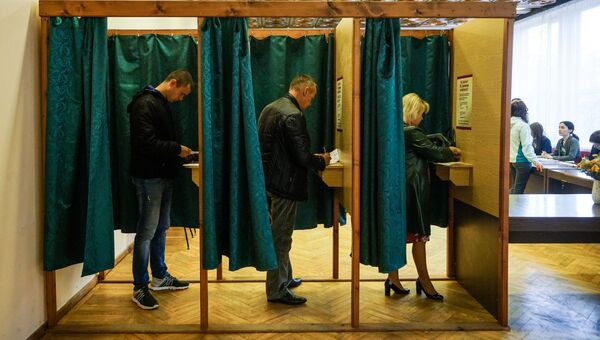 Избиратели голосуют на избирательном участке в Огре во время парламентских выборов в 13-й Сейм Латвии. 6 октября 2018