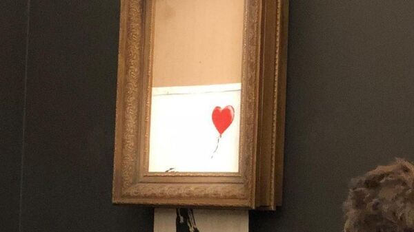 Работа художника Бэнкси Девочка с шаром во время самоуничтожения на аукционе Sotheby's в Лондоне