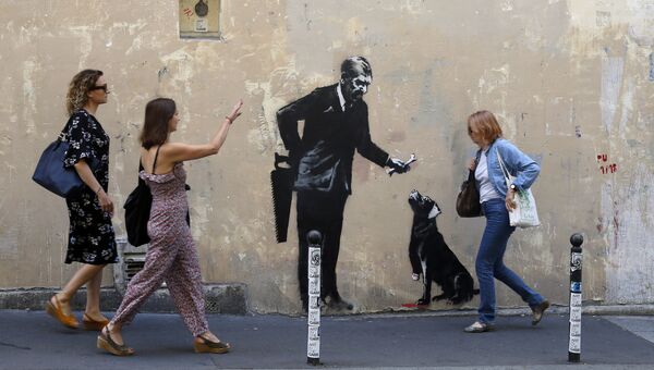 Прохожие у граффити британского художника Бэнкси в Париже, Франция
