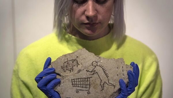 Сотрудница Национального музея Британии держит работу Бэнкси под названием Пекхамский камень
