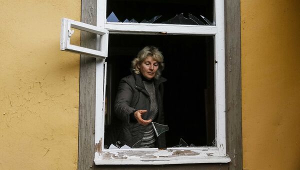 Местная жительница осматривает окно, выбитое в результате взрыва на военном складе в Черниговской области. 9 октября 2018