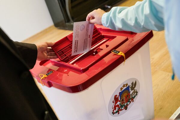 Избиратель опускает бюллетень в урну во время парламентских выборов в Латвии Избиратель опускает бюллетень в урну во время парламентских выборов в Латвии