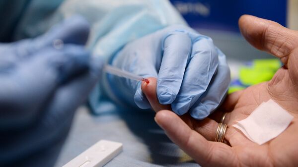 Медицинский работник производит экспресс-анализ крови в мобильном пункте центра профилактики и лечения ВИЧ-инфекции