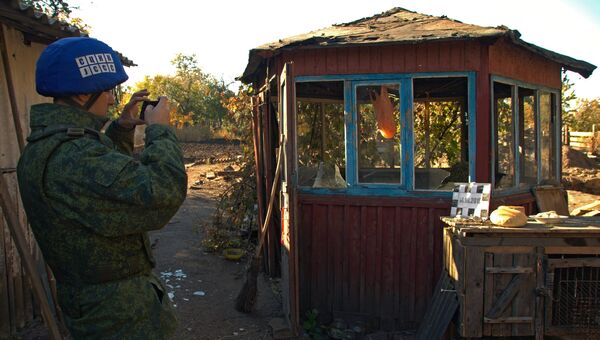 Сотрудник Совместного центра контроля и координации режима прекращения огня изучает последствия обстрела поселка Марьевка в Луганской области. 14 октября 2018