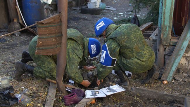 Сотрудники Совместного центра контроля и координации режима прекращения огня изучают последствия обстрела поселка Марьевка в Донецкой области. Архивное фото