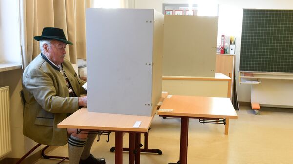 Мужчина в традиционной баварской одежде заполняет бюллетень для голосования на избирательном участке в Нойкирхене, Германия