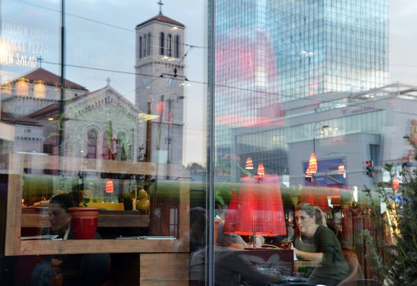 Собор св. Иосифа и небоскреб отражаются в витрине кафе города Сараево