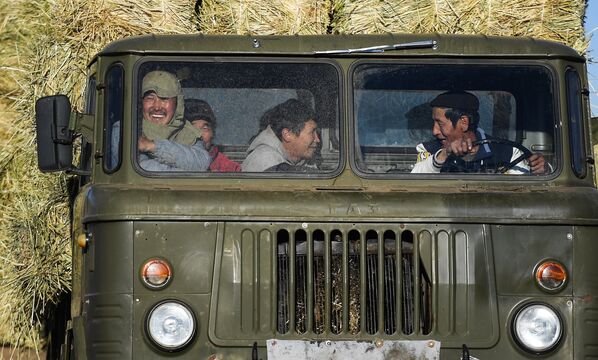 Работники в кабине грузовика во время сбора сена в монгольской степи