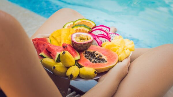 Девушка с фруктами отдыхает у бассейна