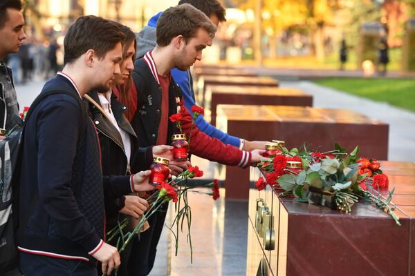 Люди возлагают цветы и ставят свечи на памятник городу-герою Керчи в Александровском саду в Москве в знак траура по погибшим при взрыве в колледже в Керчи