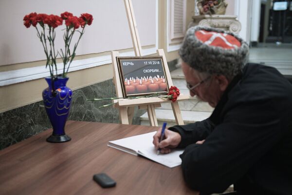 Мужчина оставляет запись в книге соболезнований в Санкт-Петербургском Доме национальностей в связи с происшествием в Керченском политехническом колледже