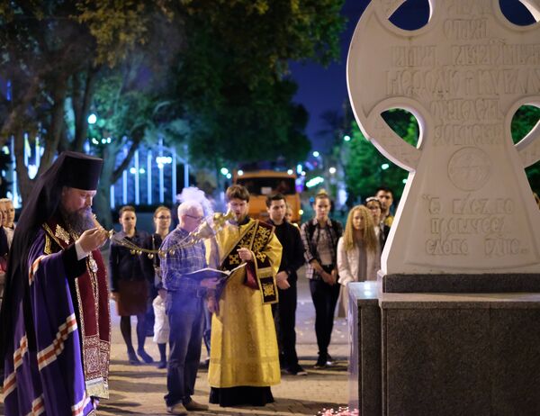 Священнослужитель читает молебен у импровизированного мемориала в Краснодаре в память о погибших при нападении на керченский колледж