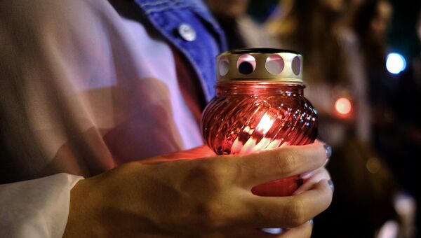 Лампадка в руках у жительницы Краснодара во время акции памяти о погибших при нападении на керченский колледж