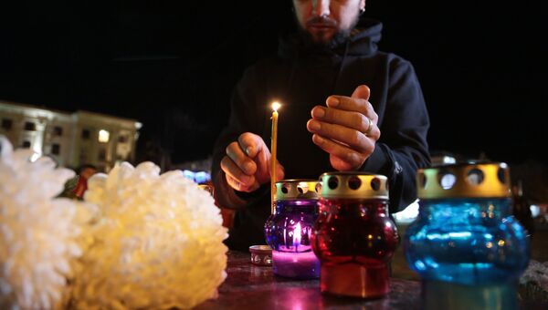 Мужчина зажигает свечу у народного мемориала в Симферополе в память о погибших при нападении на керченский колледж