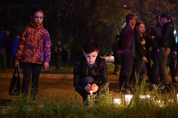 Женщина со свечой на улице в Керчи, где в Керченском политехническом колледже произошли взрыв и стрельба