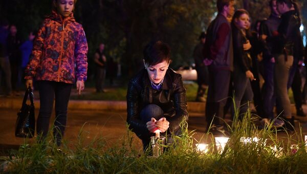 Женщина со свечой на улице в Керчи, где в Керченском политехническом колледже произошли взрыв и стрельба