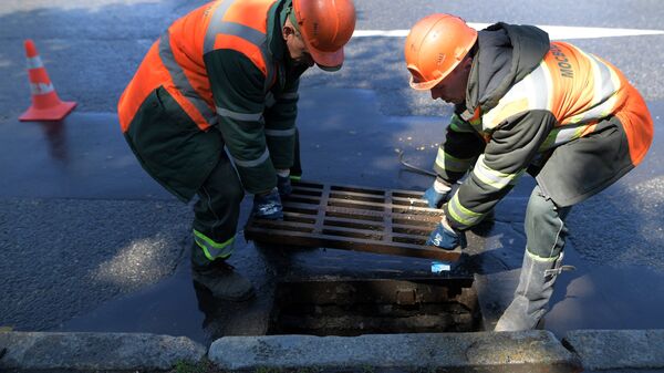 Сотрудники ЖКХ ведут работы по очистке от мусора ливневой канализации в Москве.