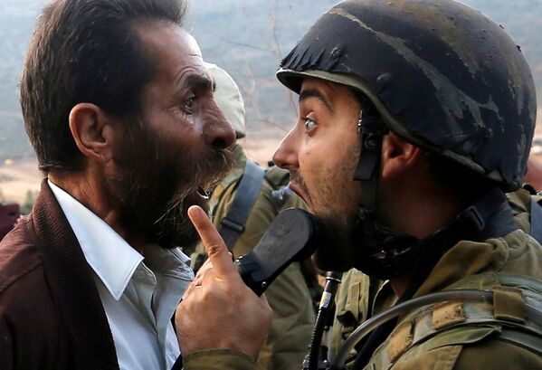 Палестинский мужчина спорит с израильским солдатом во время столкновений возле Наблуса на Западном берегу реки Иордан