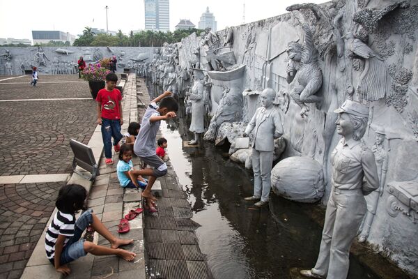 Дети играют во дворе Национального памятника Монас на площади Мердека в Джакарте