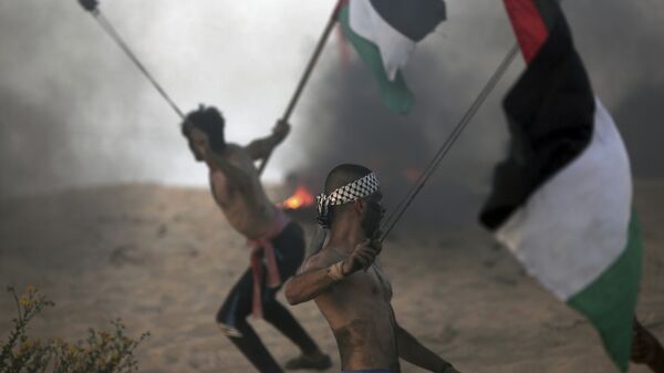 Палестинские демонстранты бросают камни в израильских военных на акции протеста возле границы вблизи Бейт-Лахии